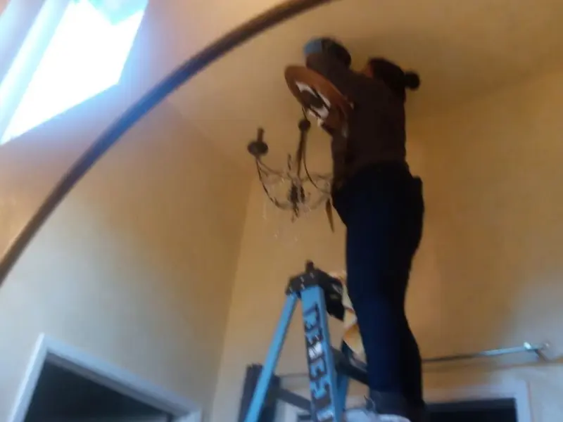 Electrician installing a chandelier in a Green residence